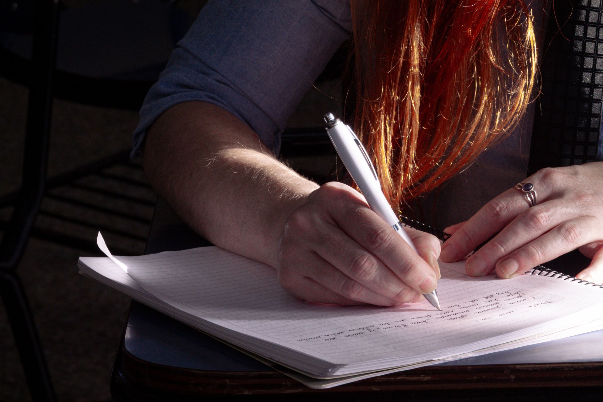 Primo piano di una mano che scrive appunti su un quaderno nella luce naturale