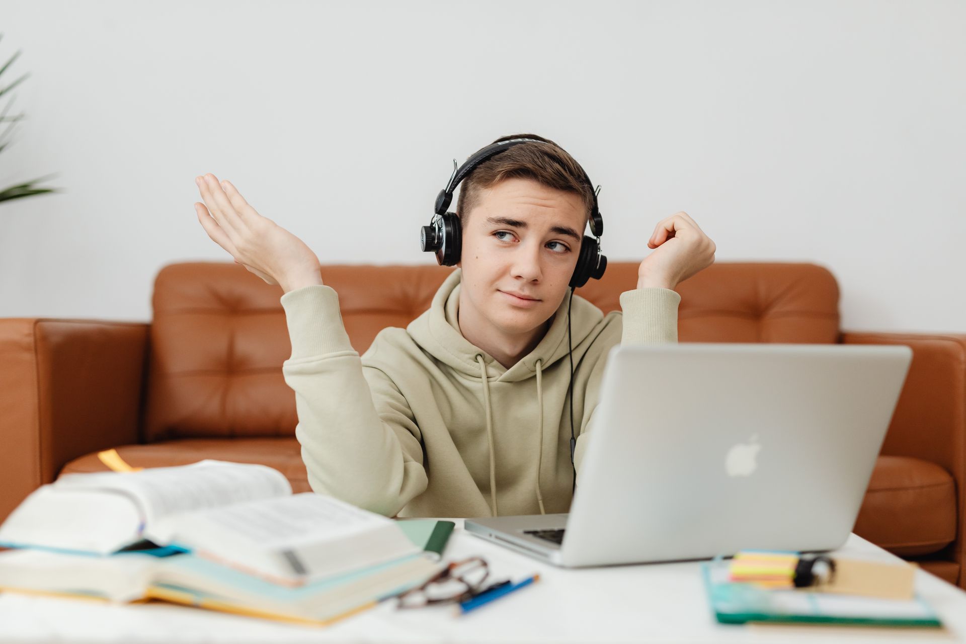 Un ragazzo con le cuffie segue una lezione online sul portatile, alla scrivania di casa