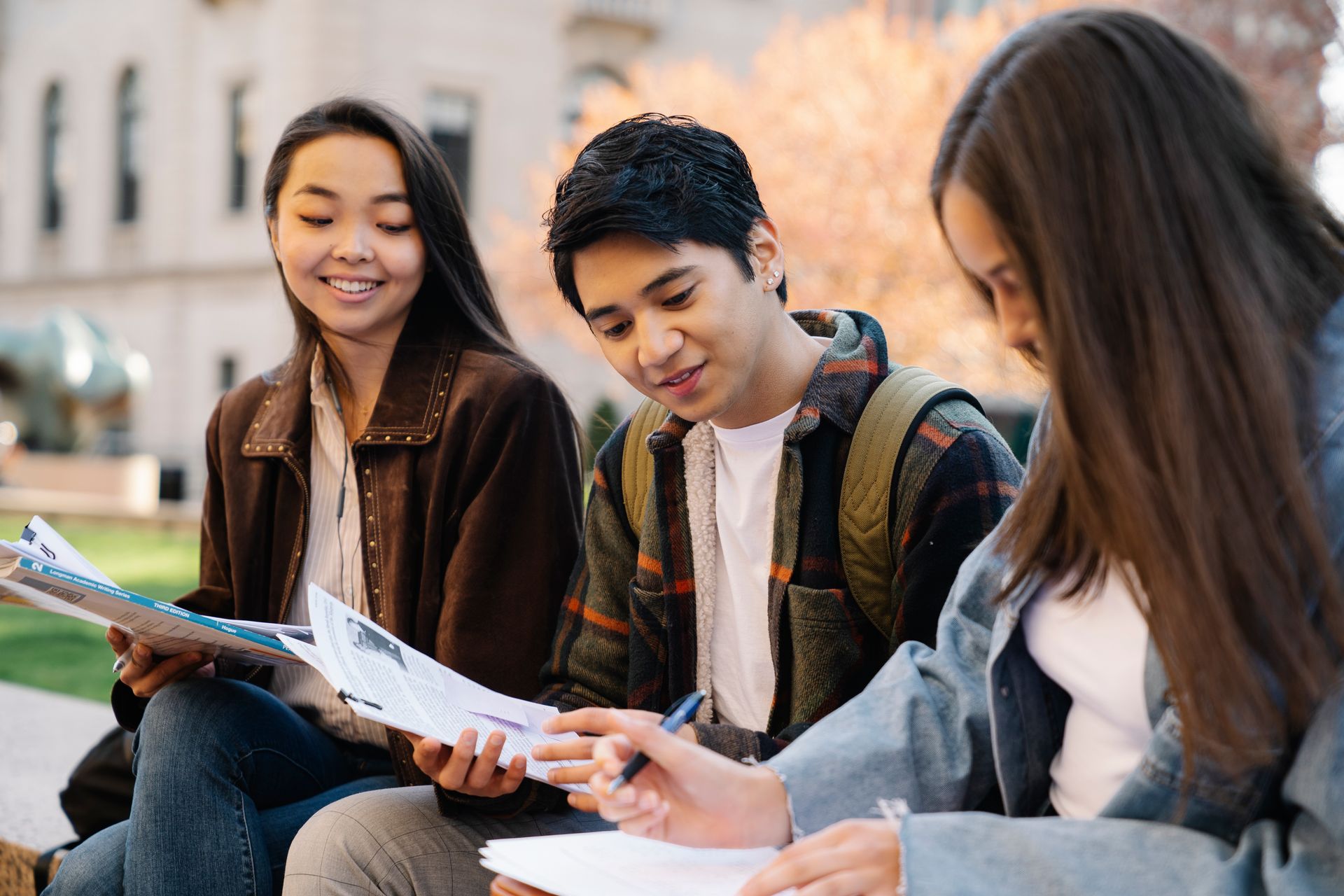 Un gruppo di studenti studia insieme all'aperto, seduti sui gradini con quaderni e portatili